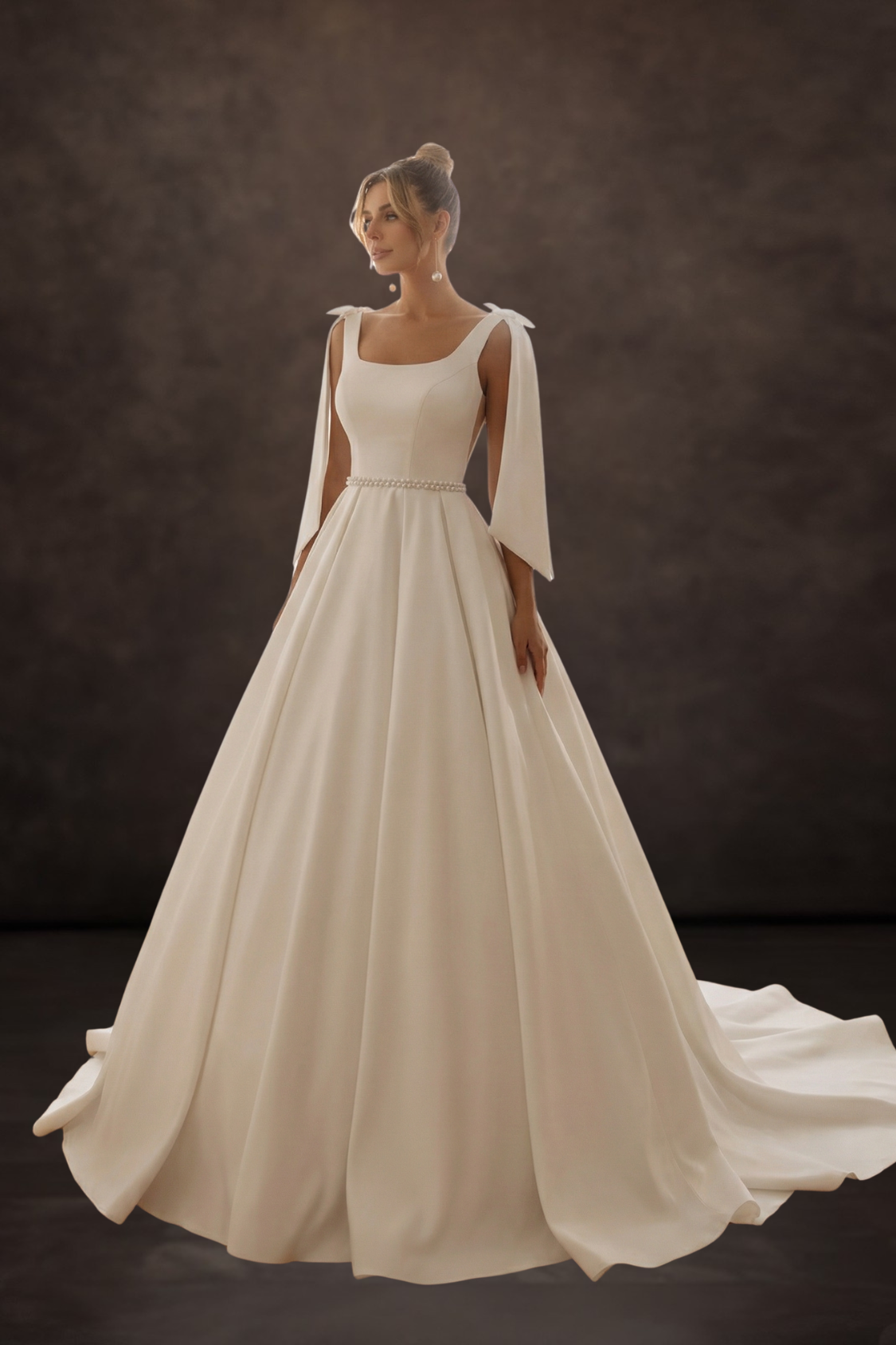 Woman wearing a white wedding dress with cape sleeves against a dark background. The Bridal House Ballito